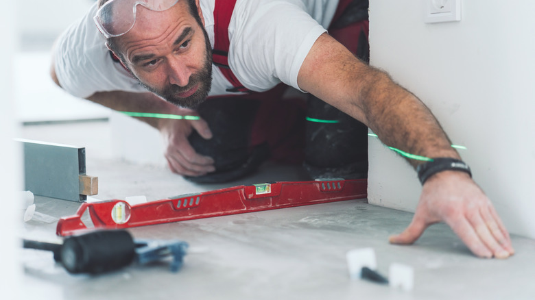 A man using spirit level to lay tiles 