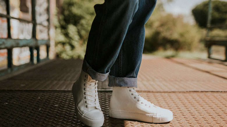 a person wearing cuffed jeans and white sneakers