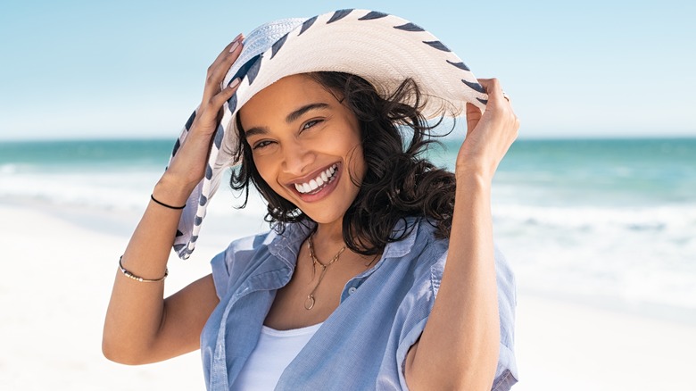 woman smiling near beach wearing hat