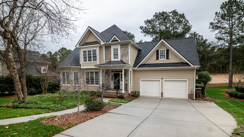 A taupe house with a black roof has a neat front yard