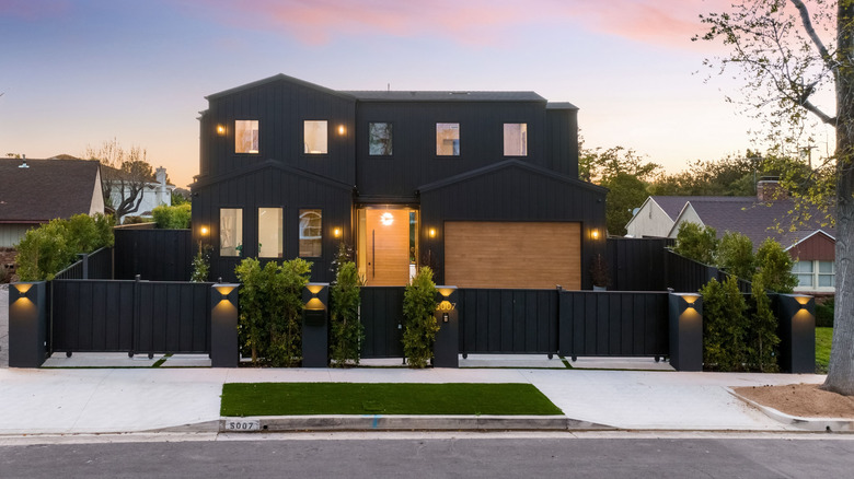 An all-black contemporary house is surrounded by a black privacy fence