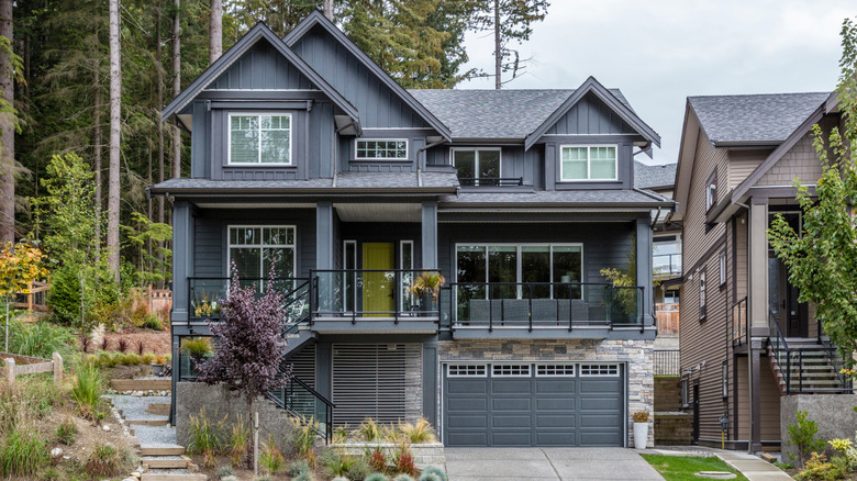 A home in the Pacific Northwest with a lime green front door is painted charcoal gray