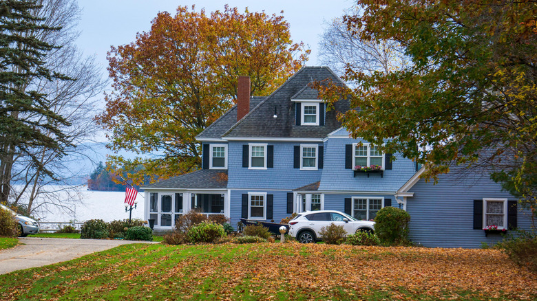 A car sits in the driveway of a cornflower blue house