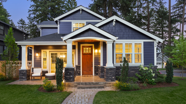 Colorful landscaping is in front of a navy blue house at dusk