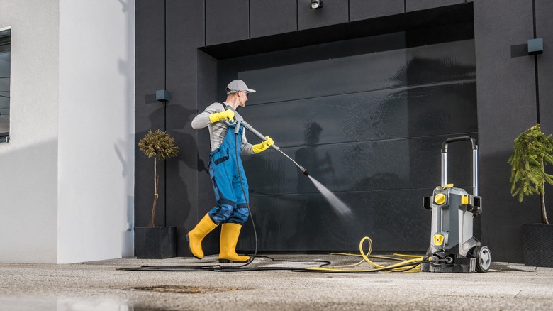 man pressure washing driveway