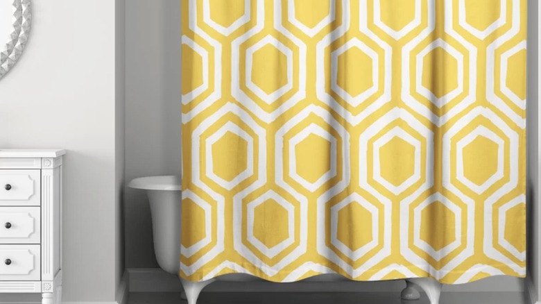 Yellow patterned shower curtain in light gray bathroom