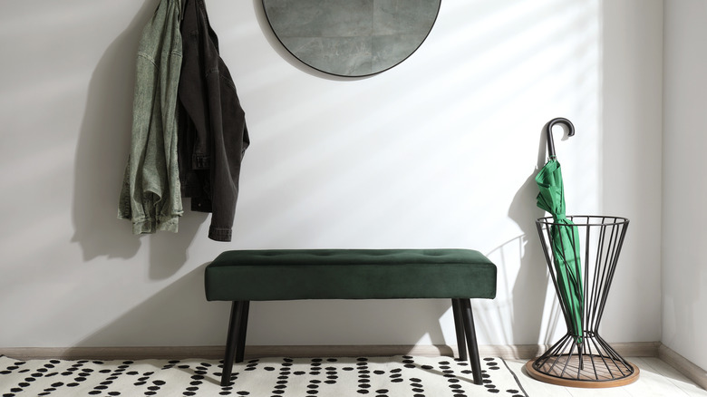 A tufted bench next to a wire umbrella stand