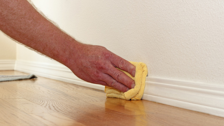 hand wiping baseboards