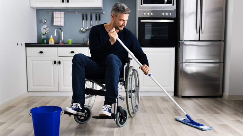 man in wheelchair mopping kitchen floor