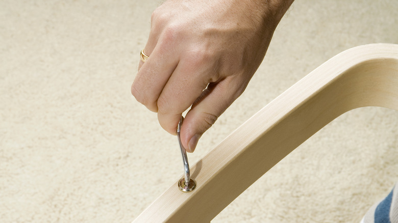 A hand assembling furniture with Allen wrench.