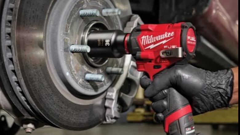 A hand using an impact wrench on a tire.