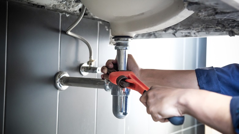 A person using a pipe wrench.