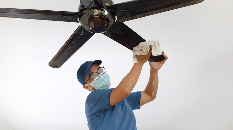 Man wiping down ceiling fan blades