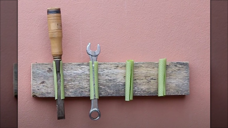 Mounted tools on a wall held up by garden hose pieces