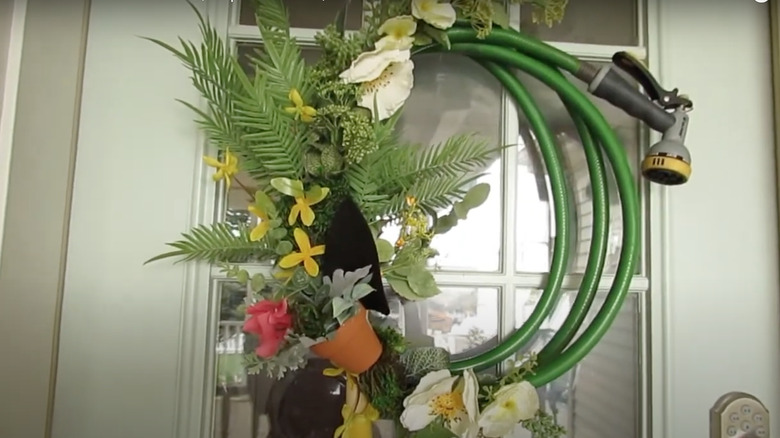 Handmade wreath made from a garden hose with garden items as decorative features