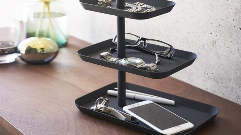 Black tiered tray with glasses, phone, keys and other items