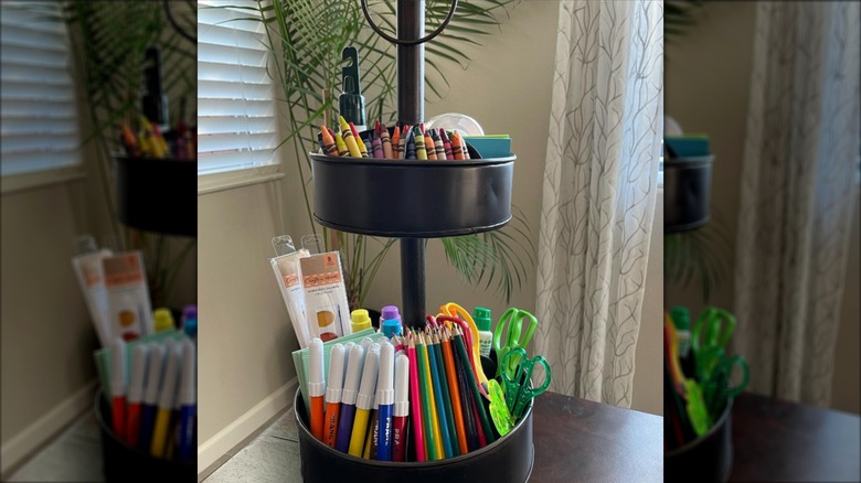 Scissors, markers, and crayons in tiered black tray