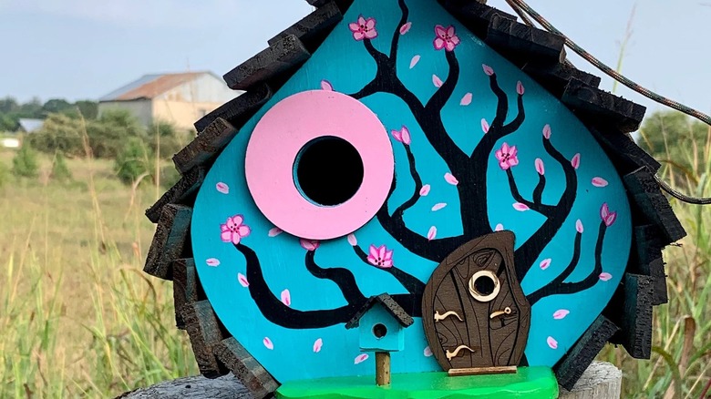 curved wooden birdhouse with colorful paint