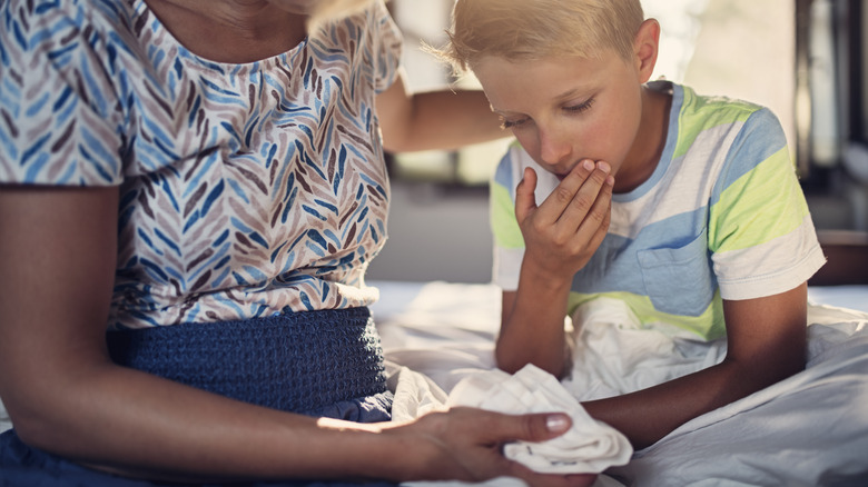 Little boy about to vomit into a cloth