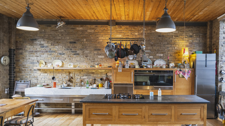 Industrial style kitchen with wooden cabinets and brick walls