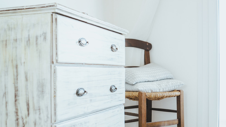 Shabby chic white dresser next to chair