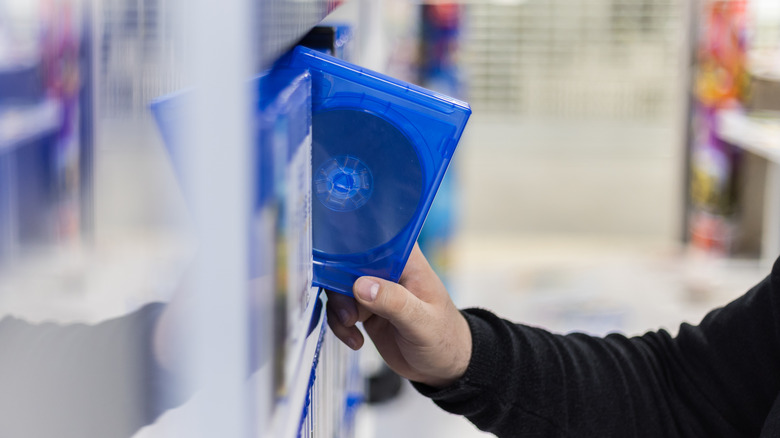 Person reaching for a blu-ray disc on a shelf