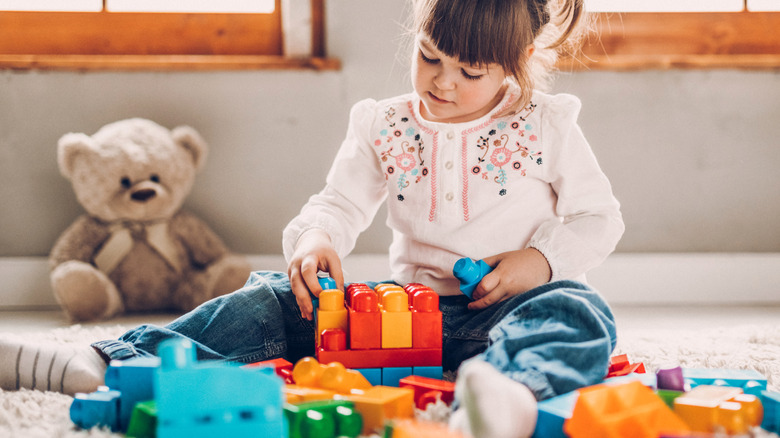 Little girl sitting on the floor playing with toys