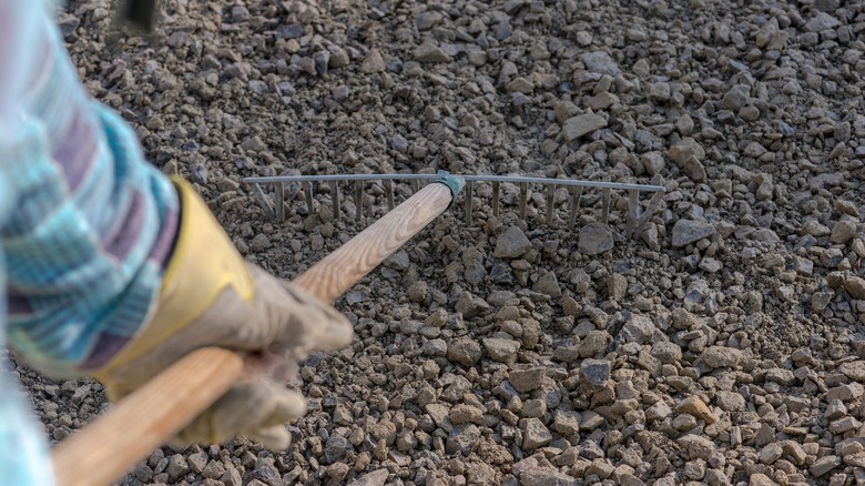 Person using a rake to level gravel for a driveway