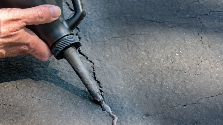 Person filling in an asphalt crack