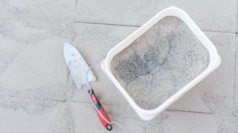 Overhead shot of a bucket with polymeric sand over paving stones