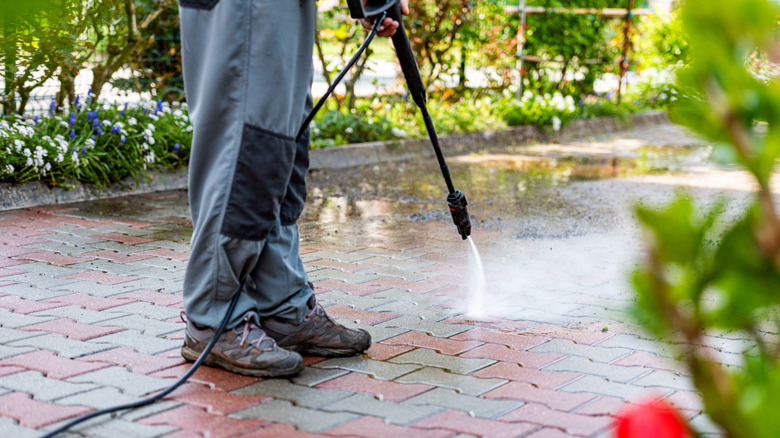 Person pressure washing a paved area