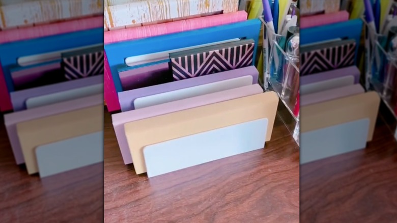 Stack of eyeshadow palettes in file holder on vanity