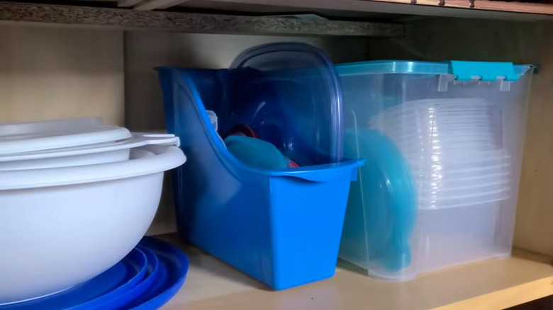 Blue file holder holding food container lids in kitchen cabinet