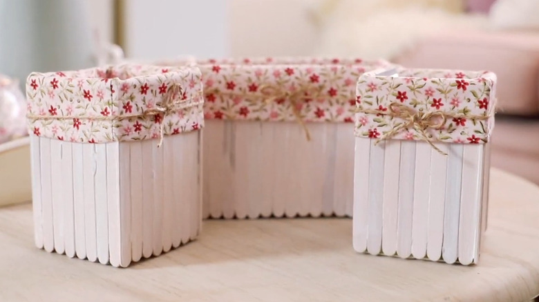 Repurposed milk cartons made into a shelf organizer adorned with fabric and twine