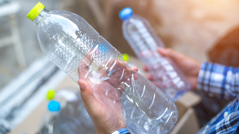 Hands holding two empty plastic bottles