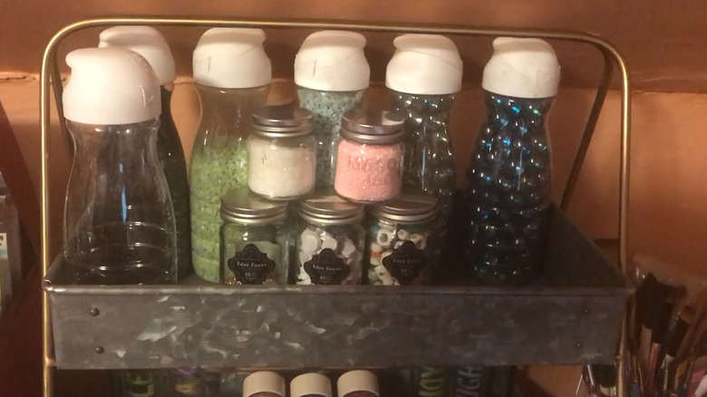 Collection of plastic creamer bottles in a metal box, each storing beads or other craft material