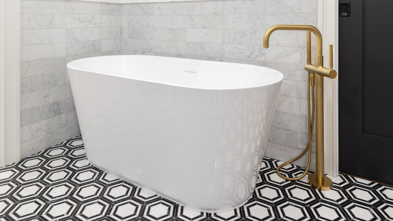 Hexagonal black and white tile on bathroom floor under white bathtub