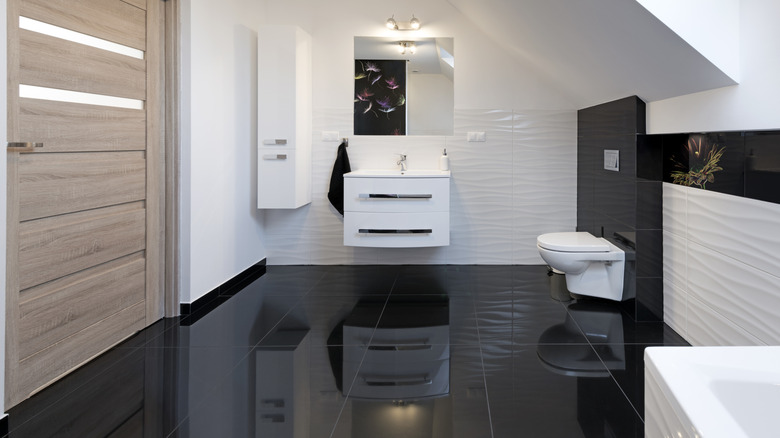 Large glossy black tiles on floor with wooden door