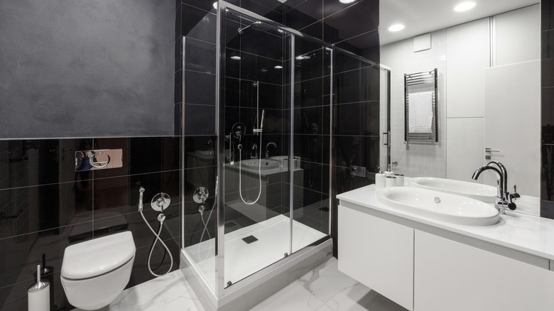 Large block black tiles covering bathroom walls and white marble floors