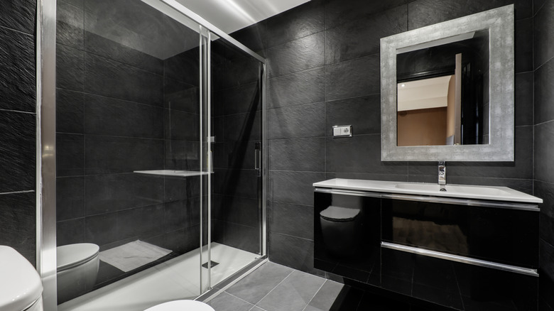 Black matte textured tiles on bathroom walls and shower