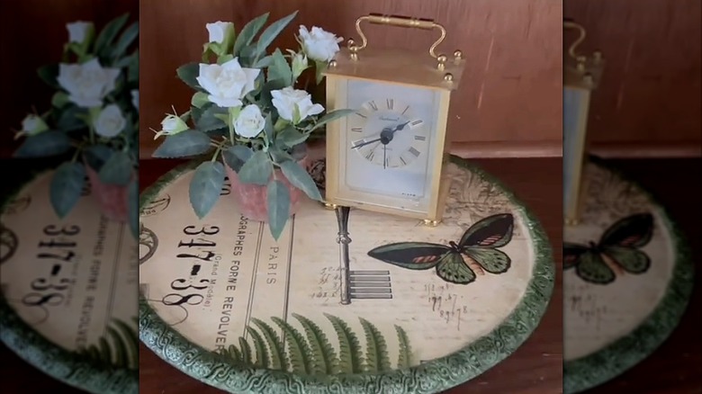 A lazy Susan displayed with a clock and faux flowers