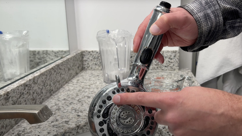 man cleaning detached stainless steel shower head