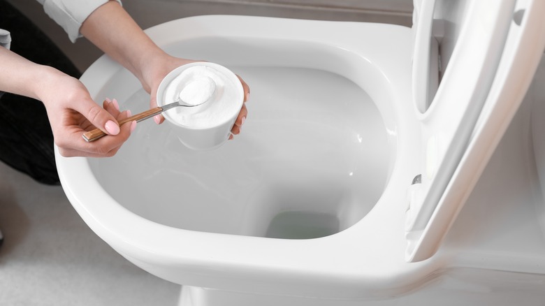 woman putting baking soda in clean toilet