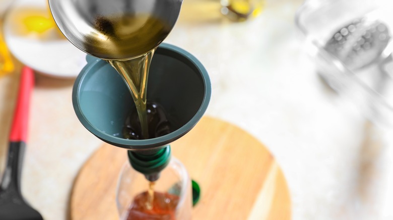 person pouring liquid into bottle