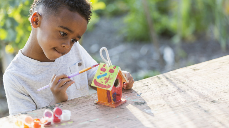 child painting a birdhouse