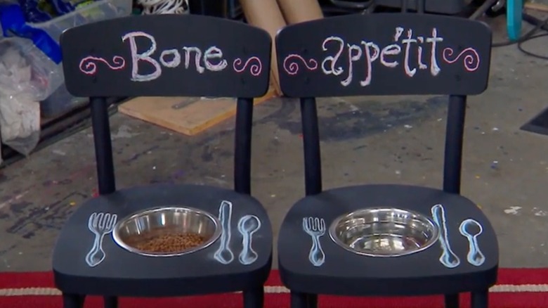 Two chairs painted black with dog bowls in seats