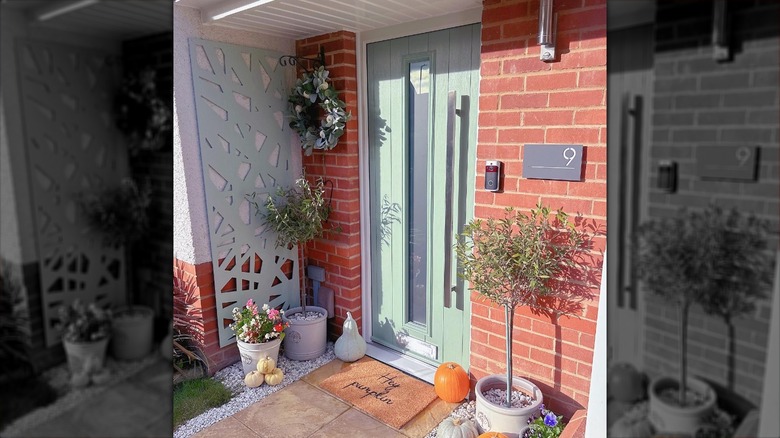 Green front door with pumpkins