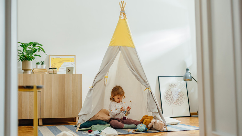Child sitting in play tent