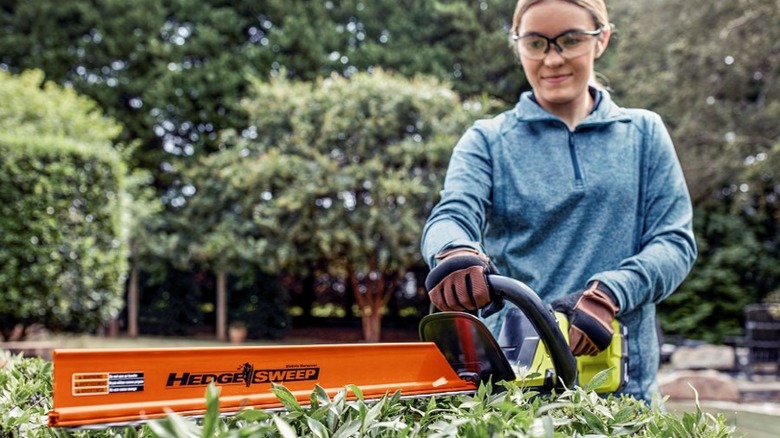 Woman using hedge trimmer