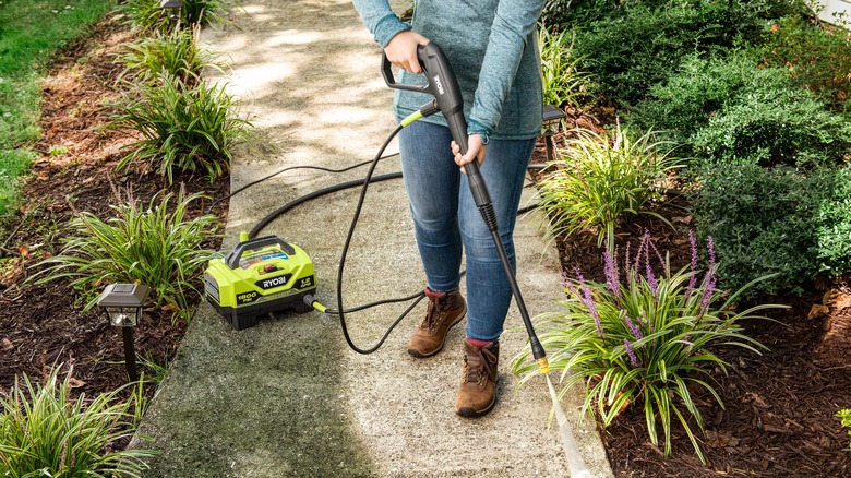 Woman pressure washing walkway